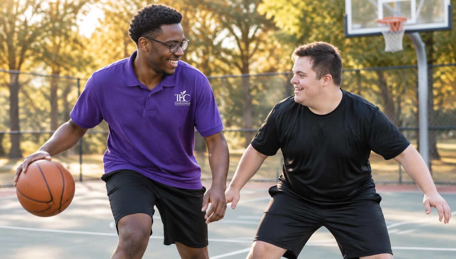 A TEC staff professional in a purple polo playing basketball with an adult participant in unbranded athletic clothing